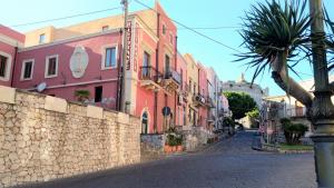 una strada cittadina con edifici colorati e un muro di pietra di B&B Micucco a Milazzo