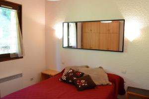 1 dormitorio con cama roja y espejo en la pared en Hameau 4 saisons 124C - Appartement 5 pers - Chatel Reservation, en Châtel