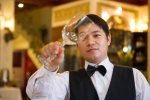 un hombre en esmoquin sosteniendo un vaso en Thuy Anh Hotel, en Ninh Binh