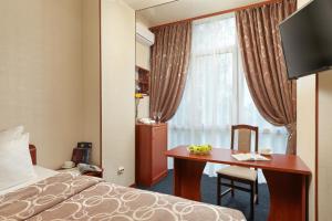 a hotel room with a bed and a desk and a window at Russky Capital Hotel in Nizhny Novgorod