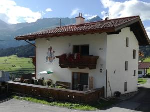a white house with a balcony with flowers on it at Apart Diamant in Nauders