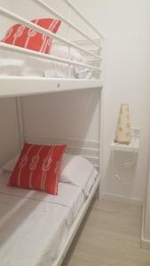 サロウにあるApartamento vacacionalの白い二段ベッド(赤と白の枕付)