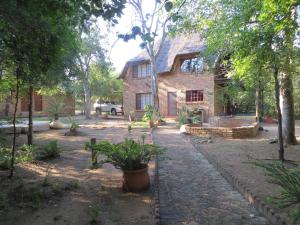 a house in the middle of a yard with trees at Kruger Safari Animal Encounter in Marloth Park