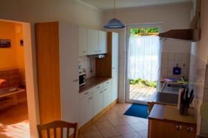 a kitchen with white cabinets and a door to a patio at Ferienhaus Doris in Dwasieden