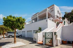a white house with a car parked in a parking lot at Luxury Apartments with private swimming pool in Marbella