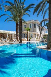 a swimming pool with palm trees in front of a house at Elegance East Hotel in Antalya