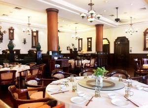 Hotel Majapahit Surabaya MGallery في سورابايا: غرفة طعام بها طاولات وكراسي وثريات