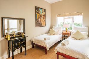 a bedroom with two beds and a mirror and a table at Antrim Luxury Villa in Cape Town