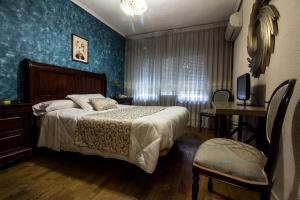 Schlafzimmer mit einem Bett, einem Tisch und einem TV in der Unterkunft Hostal Goya Suites in Salamanca