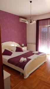 1 dormitorio con 1 cama grande y pared morada en Apartment Adriana, en Trogir