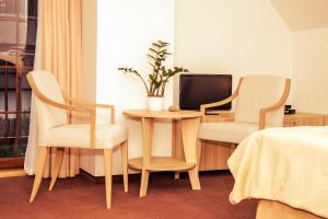 ミエンジボジェにあるUrlop Przy Wydmachのテーブル、椅子2脚、テレビが備わる客室です。