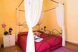 una camera con letto rosso a baldacchino di B&B L'Albero Dei Limoni a Portoscuso