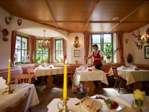 a woman standing in a dining room with tables at Naturhotel Rügers Forstgut in Mespelbrunn