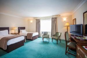 ein Hotelzimmer mit zwei Betten und einem Flachbildfernseher in der Unterkunft The Walnut Tree Hotel in Bridgwater