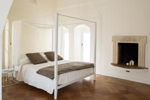 a bedroom with a white canopy bed with a fireplace at La Corte Dei Cavalieri in Matera
