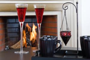 two glasses of red wine on a table with a fireplace at Noiva do Mar in Lourinhã
