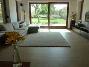 sala de estar con sofá y jarrón con flores en Villa Holiday, en Poroszló