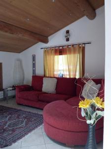 un soggiorno con divano rosso e vaso con fiori di Red House a Valdidentro