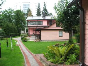 una casa rosa con parque infantil en un patio en Pansionaat Valentina en Narva-Jõesuu