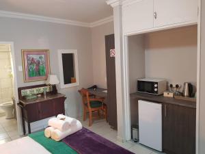a room with a bed and a kitchen with a microwave at JS Inn in Nelspruit