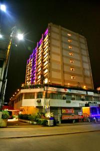 un gran edificio con luces moradas por la noche en Hotel Poonja International, en Mangalore