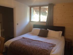 a bedroom with a white bed with a window at Chalet Marmotte 3 in Morzine