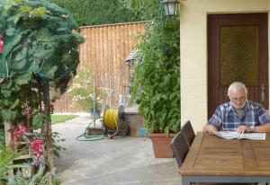 un hombre sentado en una mesa leyendo un libro en Ferienwohnung Eichler, en Feldkirchen in Kärnten