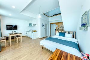 a bedroom with a bed and a desk and a kitchen at Jeju Aurum in Seogwipo