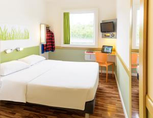 a room with a bed and a desk with a laptop at ibis budget Piracicaba in Piracicaba