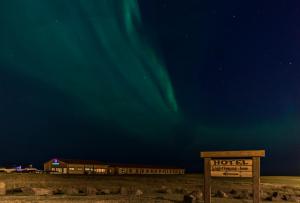 una señal frente a un hotel bajo la aurora boreal en Lighthouse-Inn, en Gardur