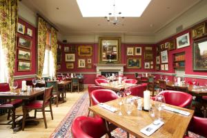 um restaurante com mesas de madeira e cadeiras vermelhas em The Crown Hotel em Blandford Forum