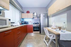ハニア・タウンにあるRafalia Cozy Apartmentのキッチン(赤いキャビネット、テーブル、冷蔵庫付)