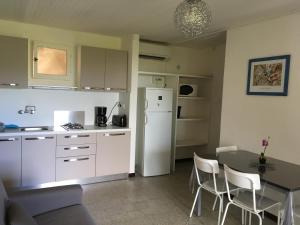 une cuisine avec une table et un réfrigérateur blanc dans l'établissement Thalassa, à Sainte-Lucie de Porto-Vecchio