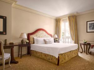 a bedroom with a bed and a desk and a window at Hôtel Métropole Monte-Carlo in Monte Carlo