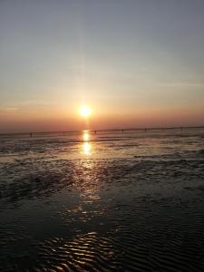 een zonsondergang op het strand met zonsondergang bij Ferienwohnung Weiser in Cuxhaven