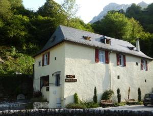 un gran edificio blanco con persianas rojas. en Maison Bergoun, en Borce