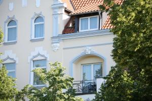 ein weißes Gebäude mit Fenstern und Bäumen in der Unterkunft Hotel An der Altstadt in Hameln