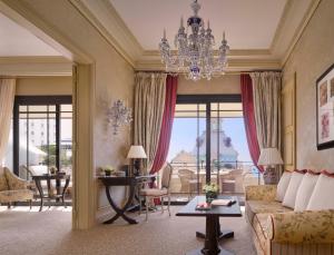 a living room with a couch and a chandelier at Hôtel Métropole Monte-Carlo in Monte Carlo