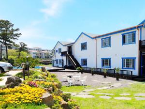 a large white building with a yard with flowers at White dream Pension in Jeju