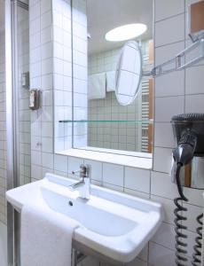 ein weißes Badezimmer mit einem Waschbecken und einem Spiegel in der Unterkunft My Südstadt Bonn in Bonn