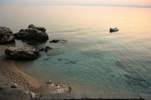 a boat in the water next to some rocks at Quercus Apartment in Stara Baška
