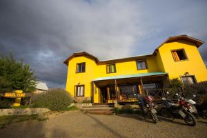 żółty dom z motocyklami zaparkowanymi przed nim w obiekcie Hostel Nakel Yenu w mieście El Calafate