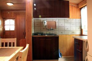 cocina con armarios de madera, fregadero y mesa en Camping Pod Krokwią en Zakopane