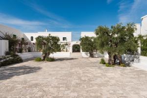 a large white house with trees in the courtyard at Masseria Il Melograno in Monopoli