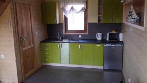 a kitchen with green cabinets and a sink and a window at Domki na Różanej 2 in Rowy +2 photos