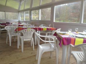 comedor con mesa, sillas y ventanas en Camping Du Pont De St Gal en Saint-Gal-sur-Sioule