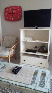 a white entertainment center with a tv and remote controls at Strandloper Apartments in Hermanus