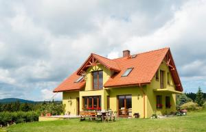 une maison jaune avec un toit orange dans l'établissement Apartamenty w Gorach Stolowych, à Szczytna