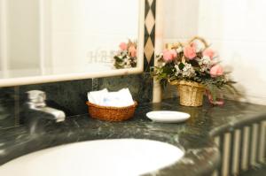 a bathroom with a sink and flowers on a counter at Hotel Barance in Alleghe