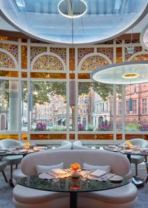 ロンドンにあるザ コノートのテーブルと椅子、大きな窓のあるレストラン